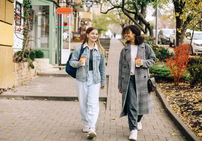 two-happy-carefree-multiracial-girlfriends-walking-city-street-with-take