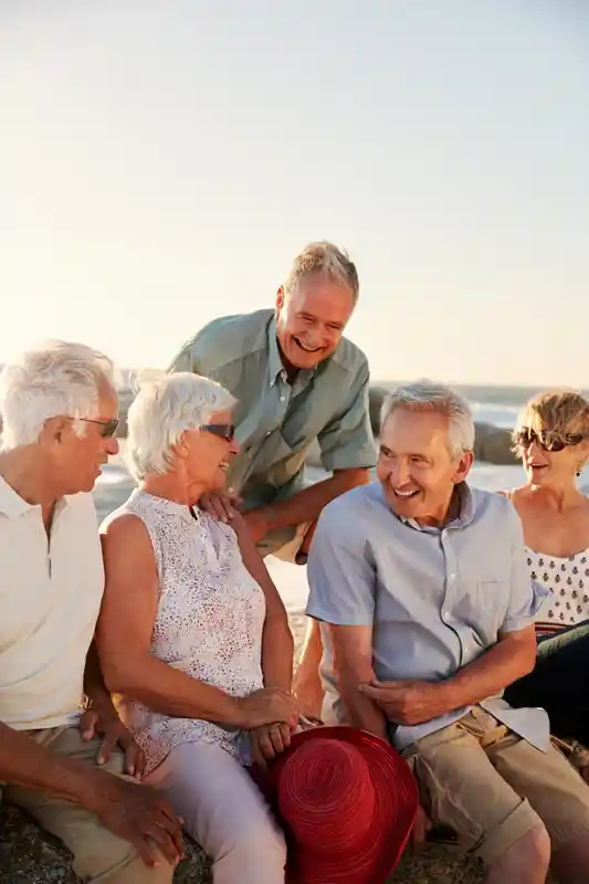group-of-senior-friends-sitting-on-rocks-by-sea-on
